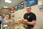Bunelos owner Paul O'Connor stands, smiling to camera while holding a tray of donuts.