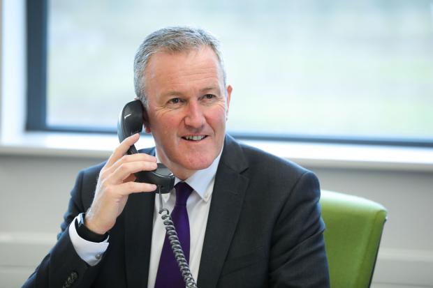 Finance Minister Conor Murphy speaking on the phone, smiling