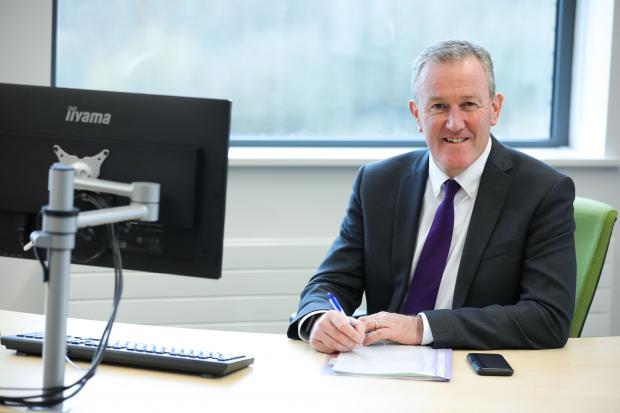 Minister Murphy sitting at his desk, smiling to camera